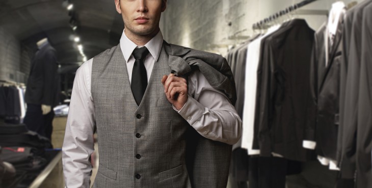 Businessman in classic vest against row of suits in shop