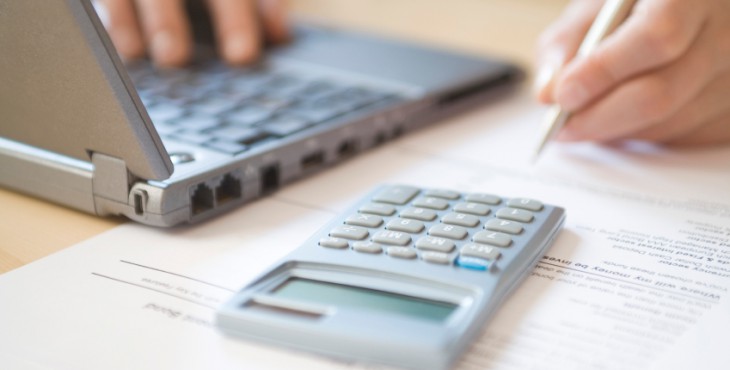 Woman's Hands Calculating Home Finances At Desk