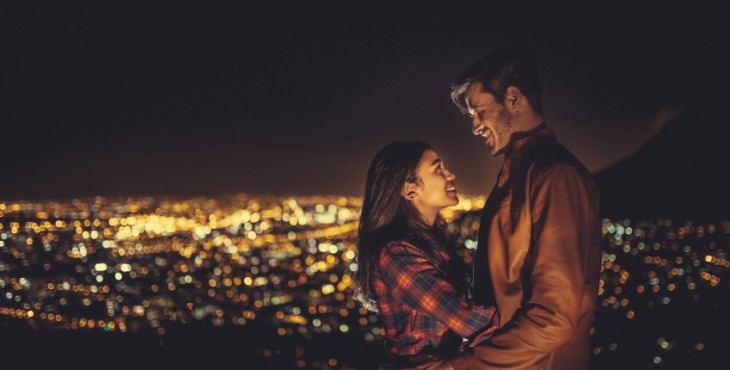 Young couple hugging at night with the city behind