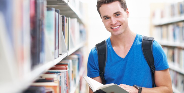Shot of a handsome young man smiling as he holds a library book