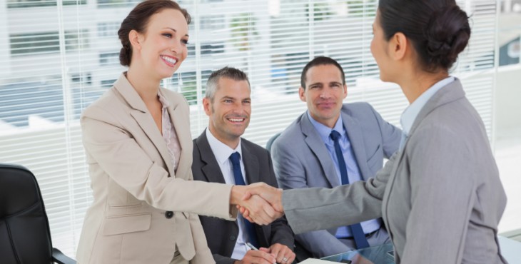 Young pretty applicant shaking hands with future employers in bright office