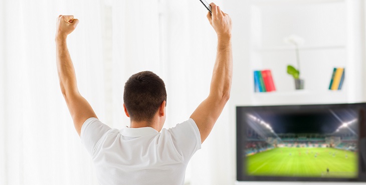 happy man watching football on tv at home