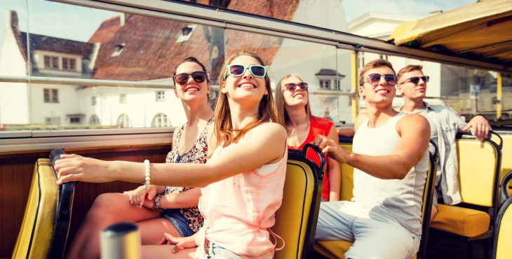 group of smiling friends traveling by tour bus